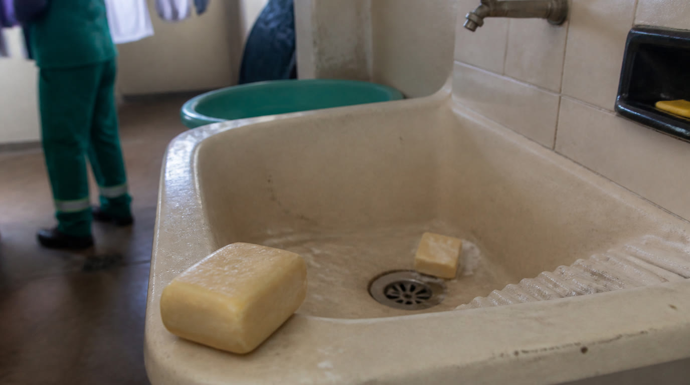 Tanque de lavar brasileiro com barras de sabão e toco dissolvendo junto ao ralo, em área de serviço residencial
